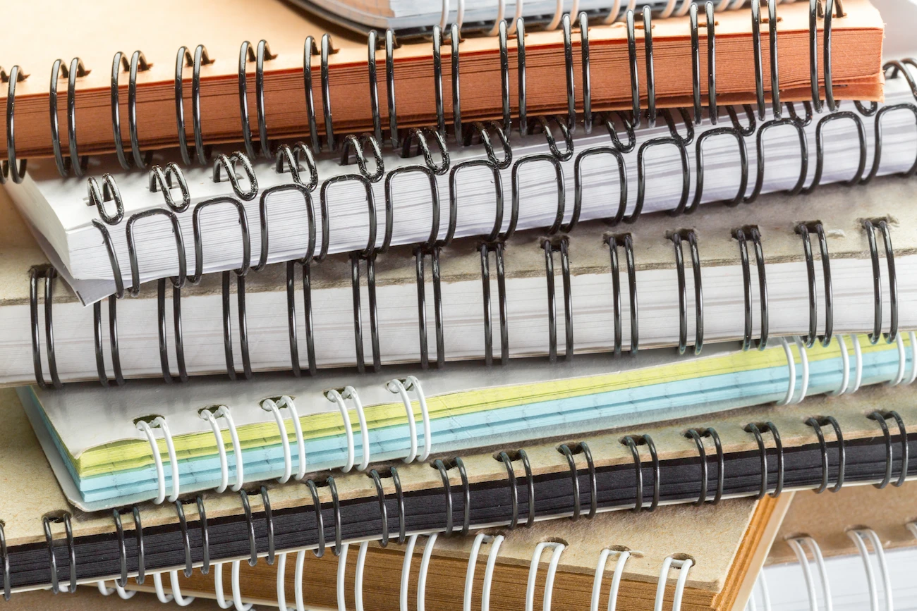 Pila de documentos y cuadernos encuadernados con espiral y wire-o en distintos colores